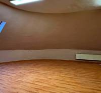 Na predaj unikátna dvojpodlažná budova na podnikanie aj bývanie - Podkrovná izba s oknom, radiátorom a podlahou s dreveným dekorom.