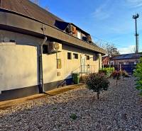 Na predaj unikátna dvojpodlažná budova na podnikanie aj bývanie - Budova v Komárne s klimatizáciou, čo obklopuje štrková plocha a kríky.