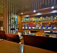 Na predaj unikátna dvojpodlažná budova na podnikanie aj bývanie - Interiér budovy s barovým pultom, ozdobnými regálmi a automatom.