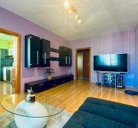 REZERVOVANÝ / NA PRENÁJOM 3 - IZB. BYT s LOGGIOU, SENICA - Obývačka 3-izbového bytu s fialovými stenami, tmavým nábytkom a TV na podlahe s dreveným dekorom.