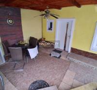 Predaj, rodinný dom Košice Juh - Terasa rodinného domu s dlažbou a sedacím nábytkom. Vo výklenku sú stôl a hodiny.