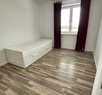 Praktický 3-izbový byt v súkromnej ulici v Šamoríne - Izba s posteľou, podlahou s dreveným dekorom a veľkým oknom v 3-izbovom byte.