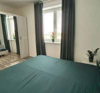 Praktický 3-izbový byt v súkromnej ulici v Šamoríne - Spálňa v 3-izbovom byte so zrkadlovou skriňou, závesmi a podlahou s dreveným dekorom.