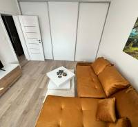 PREDAJ: 2 izbový tehlový byt-komplet.rek. - KOMÁRNO - Obývacia izba v 2-izbovom byte s podlahou s dreveným dekorom a oranžovou sedačkou.