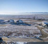 Stavebný pozemok v lokalite Medzi Vodami - Mlynica: Pozemky - bývanie so zasneženými polia a domami, obklopené lesmi a cestami.