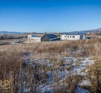 Stavebný pozemok v lokalite Medzi Vodami - Pozemky na bývanie v Mlynici s panoramatickým výhľadom a modernými stavbami v pozadí.