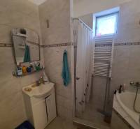 Na predaj priestranný rodinný dom Hurbanovo ! - Kúpeľňa v rodinnom dome, sprchový kút so závesom, umývadlo, zrkadlo a radiátor.