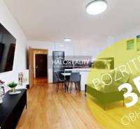 Predaj, dvojizbový byt Bratislava Ružinov, Trnavská ... - Obývačka v 2-izbovom byte s podlahou s dreveným dekorom, jedálňou a televíziou na stene.