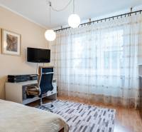 4-izbový byt, Štúrovo nábrežie Spišská Nová Ves - Izba v 4-izbovom byte s pracovným stolom, televízorom, kreslom a závesmi.