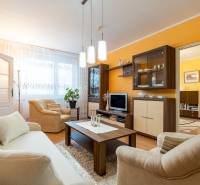 4-izbový byt, Štúrovo nábrežie Spišská Nová Ves - Obývačka v 4-izbovom byte s pohovkou, kreslami a podlahou s dreveným dekorom.