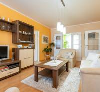 4-izbový byt, Štúrovo nábrežie Spišská Nová Ves - Obývacia izba v 4-izbovom byte s podlahou s dreveným dekorom a oranžovou stenou.