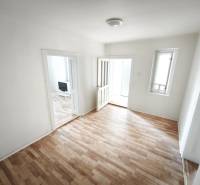 Rodinný dom - Lúčnica nad Žitavou  - Izba v rodinnom dome s podlahou s dreveným dekorom a jednoduchým zariadením.