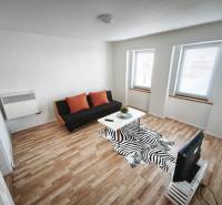 Rodinný dom - Lúčnica nad Žitavou  - Obývačka v rodinnom dome s pohovkou, stolom a podlahou s dreveným dekorom.