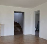 Na predaj – veľkorysý rodinný dom s úžasným výhľadom a pozemkom - Interiér rodinného domu s krbom, schodiskom a podlahou s dreveným dekorom.