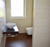 Na predaj – veľkorysý rodinný dom s úžasným výhľadom a pozemkom - Kúpeľňa v rodinnom dome so svetlým umývadlom a podlahou s dreveným dekorom.