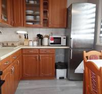 PREDAJ- 3-iz. byt, Homolova - Dúbravka, 67 m2, 11./12. posch., lodžia - Kuchyňa s dreveným dekorom, sporákom, chladničkou a jedálenským stolom v 3-izbovom byte.