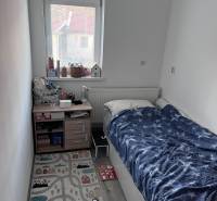 Na predaj moderný 4-izbový byt s veľkou terasou a súkromnou záhradou - Detská izba s posteľou, oknom a koberečkom v 4-izbovom byte.