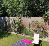 Na predaj moderný 4-izbový byt s veľkou terasou a súkromnou záhradou - Záhrada 4-izbového bytu v Bratislave - Vrakuni s kreslom a kobercom na tráve.