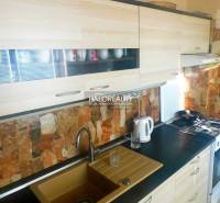 Predaj, dvojizbový byt Topoľčany, Centrum - Izba v 2-izbovom byte s podlahou s dreveným dekorom, televízorom a vstavanými skriňami.