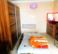 Predaj, dvojizbový byt Topoľčany, Centrum - Spálňa v 2-izbovom byte s posteľou, sedačkou a skrinkou s dreveným dekorom.