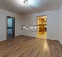 REZERVOVANÉ - Predaj, dvojizbový byt Spišská Nová Ve... - Obývacia izba v 2-izbovom byte s podlahou s dreveným dekorom a vstupom do kuchyne.