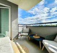 Na predaj štýlový 2-izbový byt s loggiou a parkovaním – TN, Na Pažiti - Balkón 2-izbového bytu s ratanovým nábytkom a výhľadom na mesto Trenčín na ulici Na pažiti.