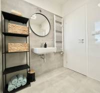 Na predaj štýlový 2-izbový byt s loggiou a parkovaním – TN, Na Pažiti - Kúpeľňa v 2-izbovom byte s umývadlom, regálom a uterákmi na dlažbe.