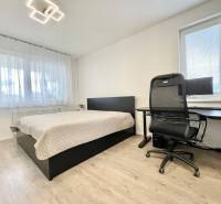 Na predaj štýlový 2-izbový byt s loggiou a parkovaním – TN, Na Pažiti - Svetlá spálňa s podlahou s dreveným dekorom v 2-izbovom byte, pracovný kút a posteľ.