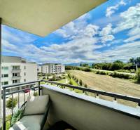 Na predaj štýlový 2-izbový byt s loggiou a parkovaním – TN, Na Pažiti - Výhľad z balkóna 2-izbového bytu na ulici Na pažiti v Trenčíne, na polia a budovy.