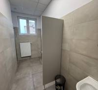 Prenájom nových kancelárskych priestorov a skladov na Teplickej ulici  - Kancelárie so sivým obkladom a záchodom, s malým oknom a rebrovým radiátorom.