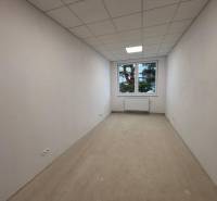 Prenájom nových kancelárskych priestorov a skladov na Teplickej ulici  - Biela miestnosť s oknom, radiátorom a podlahou s dreveným dekorom v Kanceláriách.
