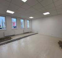 Prenájom nových kancelárskych priestorov a skladov na Teplickej ulici  - Prázdne kancelárie s bielymi stenami, stropným osvetlením a podlahou s dreveným dekorom.