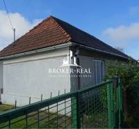 Rodinný dom Rudabanya, Maďarsko - Rodinný dom v Rudabányi s bielou fasádou a šikmou strechou za zeleným plotom.