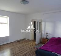 Rodinný dom Rudabanya, Maďarsko - Izba s posteľou, oknom, podlahou s dreveným dekorom, nočným stolíkom a otvorenými dverami.