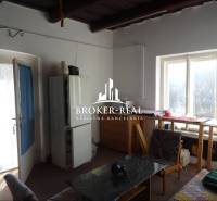 Rodinný dom Rudabanya, Maďarsko - Izba v rodinnom dome s presvetleným stolom pri okne, kreslom a jedálenským stolom.