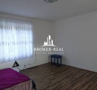 Rodinný dom Rudabanya, Maďarsko - Izba s posteľou, záclonami a podlahou s dreveným dekorom v rodinnom dome.