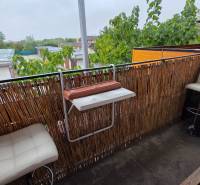 Na prenájom 3 izbový byt z balkónom a parkovacím miestom - Balkón 3-izbového bytu v Galante s moderným zábradlím a bielymi barovými stoličkami.