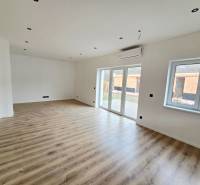 DOLINKY - Moravany nad Váhom 5 izbový bungalov - Interiér rodinného domu s podlahou s dreveným dekorom a veľkými oknami.