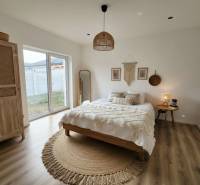 DOLINKY - Moravany nad Váhom 5 izbový bungalov - Spálňa s posteľou, okrúhlym kobercom, šatníkovou skriňou a podlahou s dreveným dekorom v rodinnom dome.