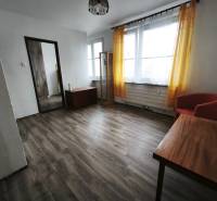 PREDAJ: 1i byt 30m2 - BAURING - FONČORDA - Orenburská ul. - Obývacia izba v 1-izbovom byte s podlahou s dreveným dekorom a žltými závesmi.