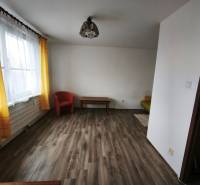 PREDAJ: 1i byt 30m2 - BAURING - FONČORDA - Orenburská ul. - Obývacia izba v 1-izbovom byte s podlahou s dreveným dekorom a žltými závesmi.