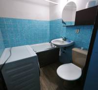 PREDAJ: 1i byt 30m2 - BAURING - FONČORDA - Orenburská ul. - Kúpeľňa s vaňou, umývadlom, toaletou a práčkou v 1-izbovom byte. Podlaha s dreveným dekorom.