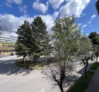 Exkluzívne | Na predaj 5i byt s garážou a záhradou v centre Ružomberka - Pohľad z 5 a viac izbového bytu na ulicu Medveckého v Ružomberku, obklopený stromami.