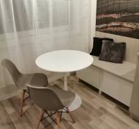 ŠIKOVNÁ GARSÓNKA na PRENÁJOM v CENTRE MESTA na BEZRUČOVEJ ul. - Jedálenský kút s okrúhlym stolom, dvomi stoličkami a dekoračnými vankúšmi, podlaha s dreveným dekorom.