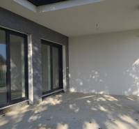 4 izbový BUNGALOV novostavba (VYSTAVBA) Piešťany, kvalitné prevedenie - Terasa rodinného domu v Piešťanoch s veľkými oknami a kamenným dekorom.