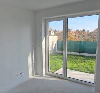 4 izbový BUNGALOV novostavba (VYSTAVBA) Piešťany, kvalitné prevedenie - Interiér rodinného domu s veľkým oknom do záhrady, biele steny a podlaha.