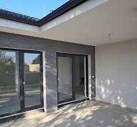 4 izbový BUNGALOV novostavba (VYSTAVBA) Piešťany, kvalitné prevedenie - Terasa rodinného domu v Piešťanoch s veľkými presklenými dverami a sivými stenami.
