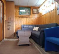 Predaj, chata Byšta - EXKLUZÍVNE HALO REALITY - Obývacia izba v Chate s pohovkou, kreslom a obkladmi na stenách.