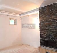 Predaj, rodinný dom Zemplín - EXKLUZÍVNE HALO REALITY - Interiér rodinného domu s kamenným krbom a malým oknom.