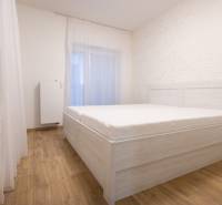 Zariadený 2i byt s lodžiou v rezidencii Pri Mýte - Spálňa v 2-izbovom byte s posteľou a podlahou s dreveným dekorom.